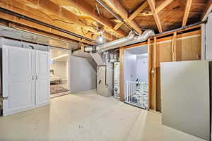 Unfinished below grade area featuring heating unit and gas water heater