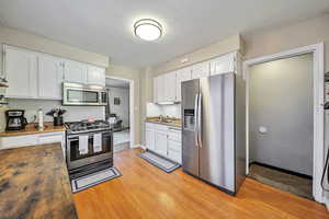 Kitchen with stainless steel appliances, light wood-type flooring, and white cabinets