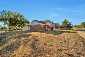 View of property exterior with brick siding, a chimney, and a garage