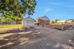 View of front facade featuring concrete driveway, a detached garage, brick siding, and an outdoor structure