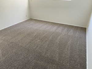 Spare room featuring carpet flooring and baseboards