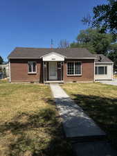 View of front of house featuring brick siding, a front yard, and roof with shingles