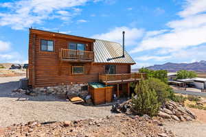 Rear view of house featuring a deck from the loft and the middle floor  with mountain view, a metal roof, and log exterior and root cellar