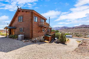 View of home's exterior featuring log siding, rock  lower level a balcony, and a deck with mountain view