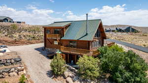 Rear view of house featuring log exterior, a balcony, a metal roof, driveway, and a deck with mountain view