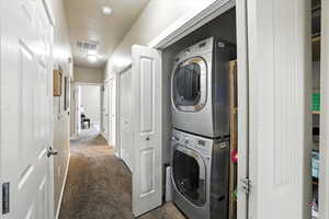 Laundry area with stacked washer / drying machine and carpet floors