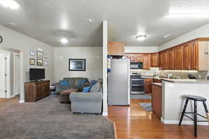 Kitchen with stainless steel appliances, a peninsula, open floor plan, a kitchen breakfast bar, and light wood finished floors