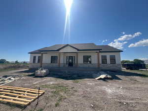 Back of property with stone siding, roof with shingles, and board and batten siding