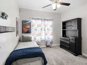 Carpeted bedroom featuring a ceiling fan and baseboards
