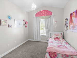 Carpeted bedroom with vaulted ceiling and a chandelier
