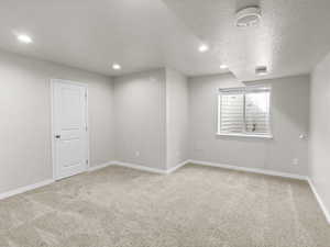 Bedroom with light carpet, recessed lighting, and a textured ceiling