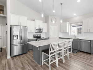 Kitchen with stainless steel appliances, a center island, decorative backsplash, light countertops, and recessed lighting