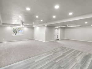 Below grade area featuring wood finished floors, recessed lighting, a ceiling fan, and carpet floors