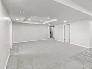 Finished basement with light wood-type flooring, recessed lighting, a textured ceiling, stairs, and light carpet