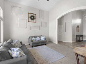 Living room featuring arched walkways, light colored carpet, a ceiling fan, and vaulted ceiling