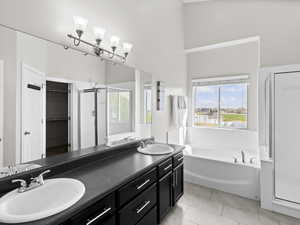 Full bath with a stall shower, a garden tub, double vanity, tile patterned floors, and a spacious closet