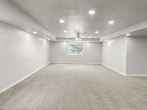 Basement featuring recessed lighting, light colored carpet, a ceiling fan, and a textured ceiling