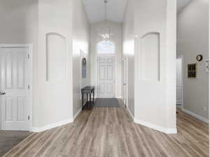 Entrance foyer featuring high vaulted ceiling, a chandelier, and light wood-style flooring