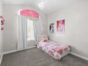 Bedroom featuring carpet, lofted ceiling, and a chandelier