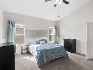 Carpeted bedroom featuring wainscoting, lofted ceiling, and ceiling fan