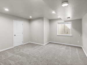 Spare room with carpet, a textured ceiling, and recessed lighting