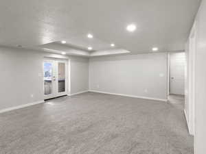 Family room with a textured ceiling, a tray ceiling, carpet flooring, recessed lighting, and french doors