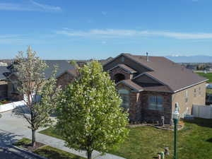 View of front of property featuring a shingled roof, brick siding, stone siding, and concrete driveway
