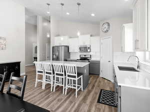 Kitchen featuring appliances with stainless steel finishes, a kitchen island, high vaulted ceiling, tasteful backsplash, and a breakfast bar