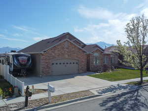View of front of property with a mountain view, an attached garage, concrete driveway, and brick siding