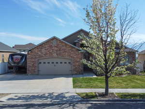 View of front of home with a garage, concrete driveway, a front lawn, and stone siding
