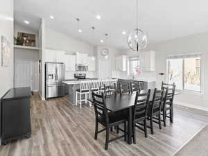 Dining area with a chandelier, light wood-type flooring, lofted ceiling, and recessed lighting