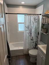 Bathroom with wood finished floors, vanity, shower / bath combo with shower curtain, and recessed lighting