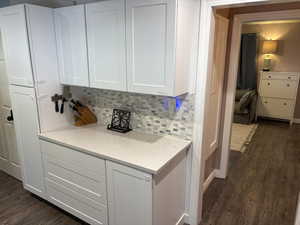 Kitchen featuring dark wood finished floors, light countertops, decorative backsplash, and white cabinets
