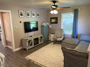 Living room featuring dark wood-type flooring and ceiling fan