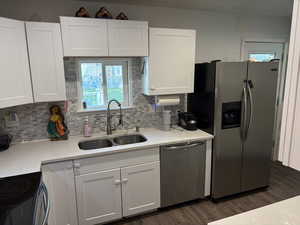 Kitchen with stainless steel appliances, white cabinets, light countertops, and tasteful backsplash