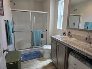Bathroom featuring a stall shower, vanity, and wood finished floors