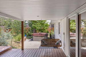 Wooden terrace featuring a hot tub and a patio area