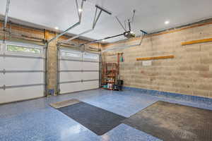 Garage featuring a garage door opener and concrete block wall