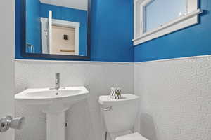 Half bath featuring a wainscoted wall and tile walls