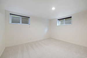 Unfurnished room featuring light carpet and baseboards