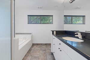 Full bath featuring vanity, a bath, and stone finish flooring