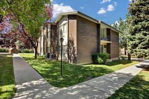 View of side of home with brick siding, a yard, and a balcony