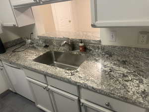 Kitchen featuring dishwasher, dark stone counters, and dark tile patterned flooring