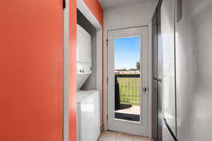 Laundry area featuring stacked washer / dryer and light tile patterned floors