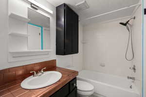 Bathroom featuring vanity, shower / washtub combination, and tasteful backsplash