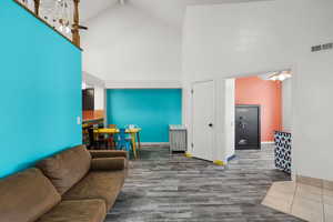 Living room featuring high vaulted ceiling, a ceiling fan, and wood finished floors