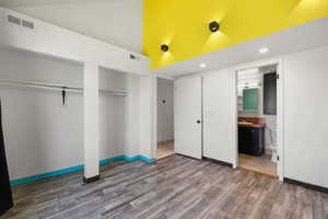 Unfurnished bedroom with high vaulted ceiling, wood finished floors, two closets, recessed lighting, and ensuite bathroom
