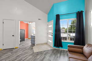 Foyer entrance with high vaulted ceiling, wood finished floors, and ceiling fan