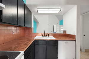 Kitchen with dishwasher, tile counters, tasteful backsplash, vaulted ceiling, and light tile patterned floors