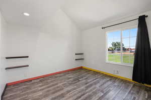 Empty room with wood finished floors, vaulted ceiling, and recessed lighting